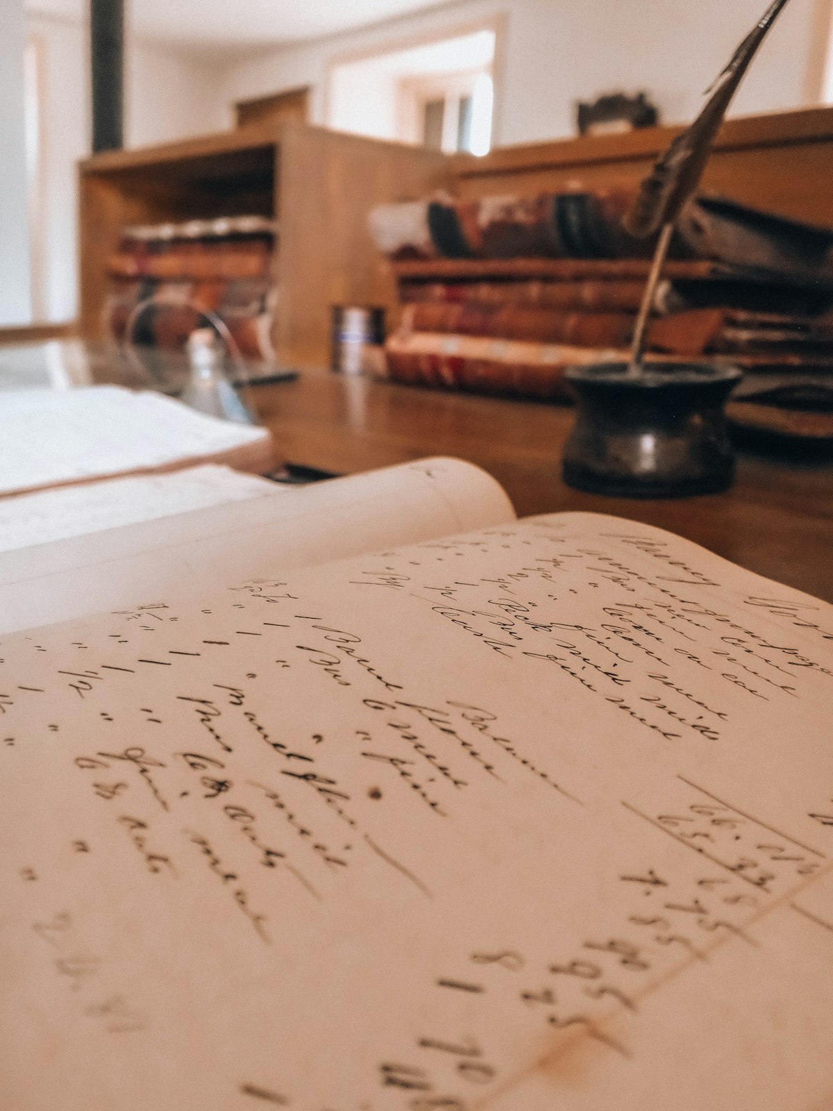 手書きの記録が残された帳簿と羽根ペン
