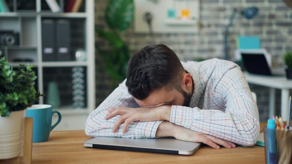 デスクで疲れた表情を見せる男性